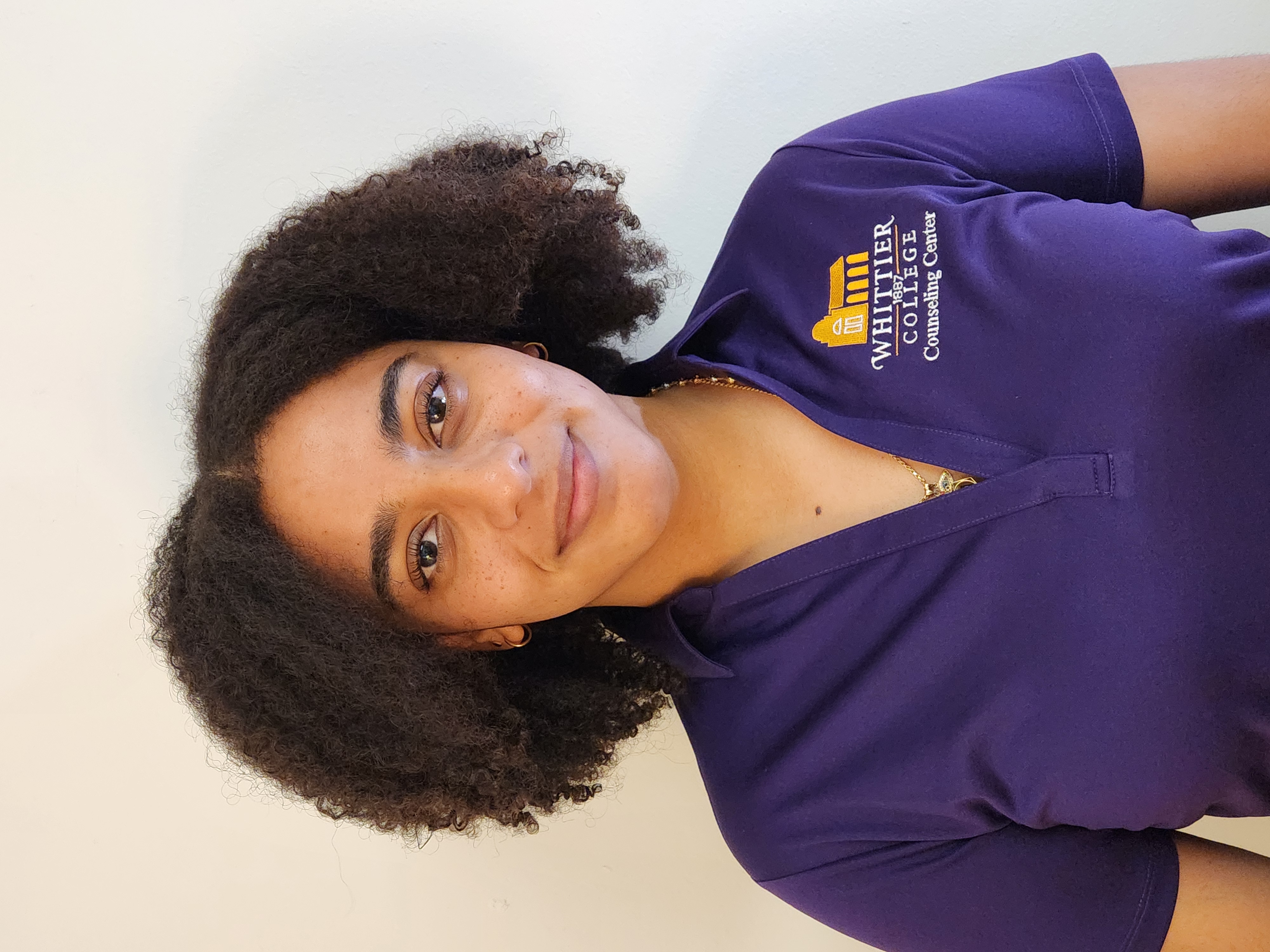 Destiny Barrientos in Whittier College purple polo shirt in front of white wall