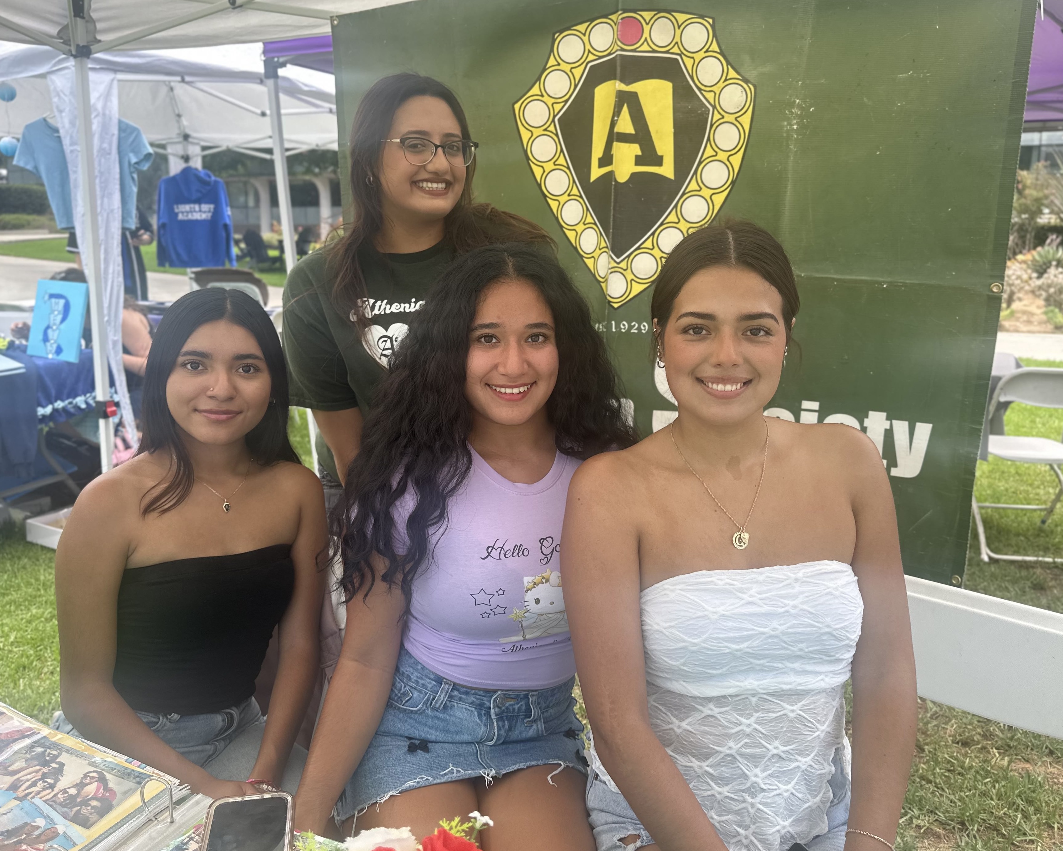 Four Female Whittier students in front of their society banner