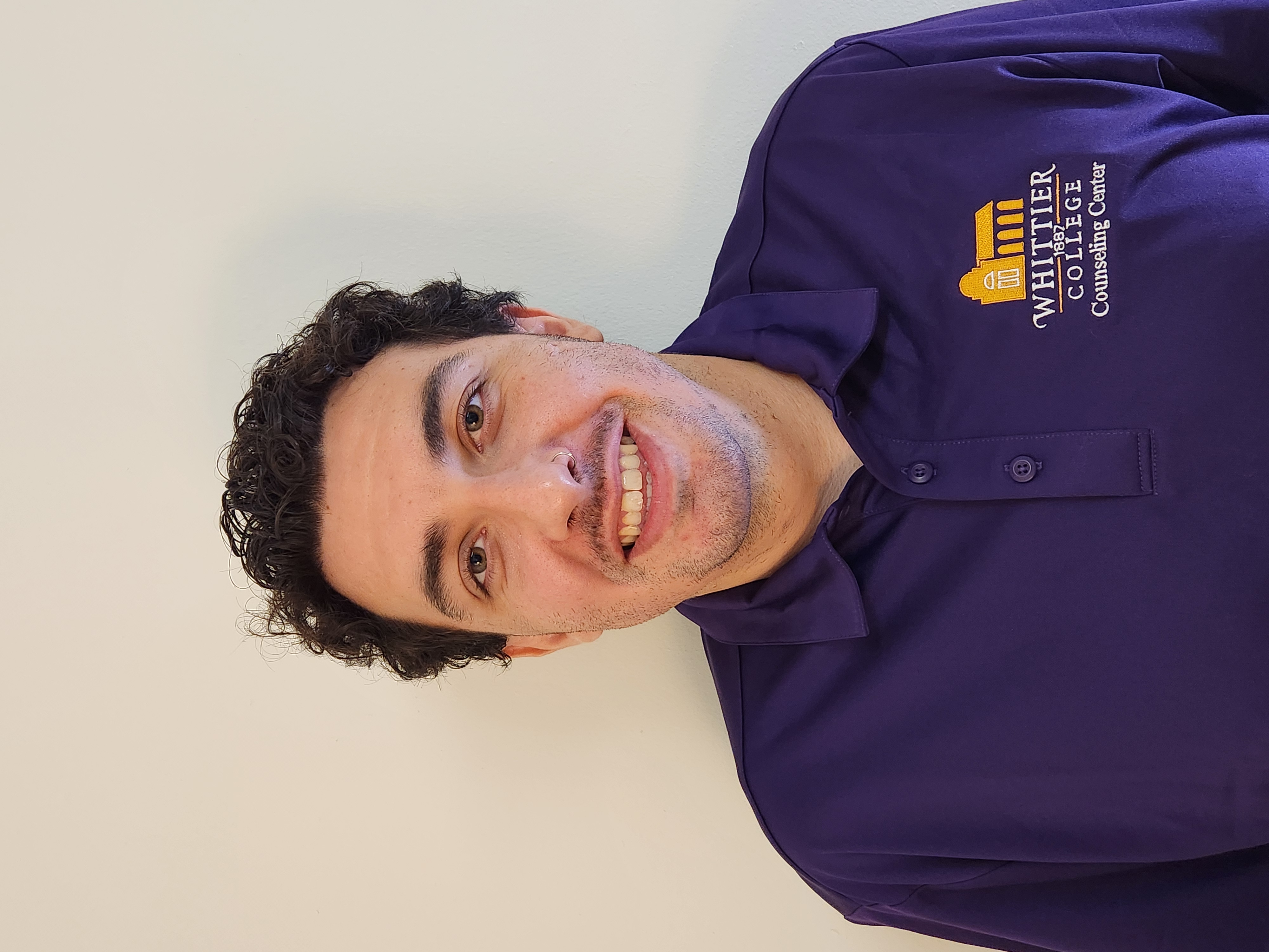 Jeremy Sanders in Whittier College purple polo shirt in front of white wall