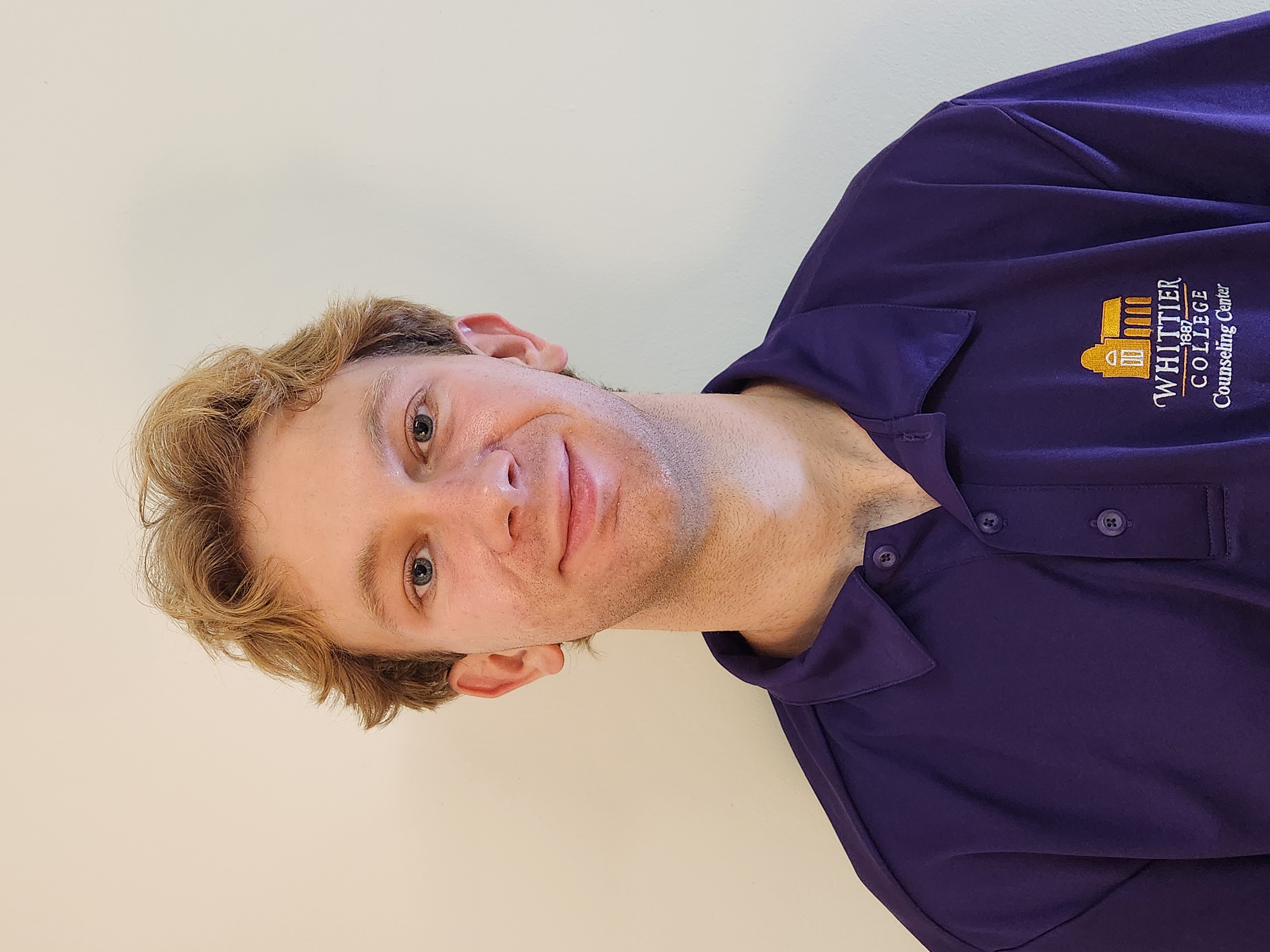 Will Oliver in Whittier College purple polo shirt in front of white wall