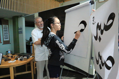 student creating calligraphy art on easel 