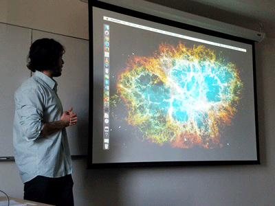 Physics majro Carlos Campos-Moya stands in front of a picture of a supernova.