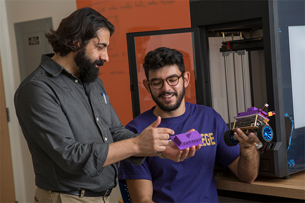 Professor Serkan Zorba and a student look at robots.