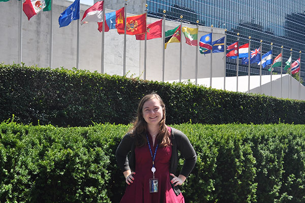 Political science student stands in front of United Nations flags.