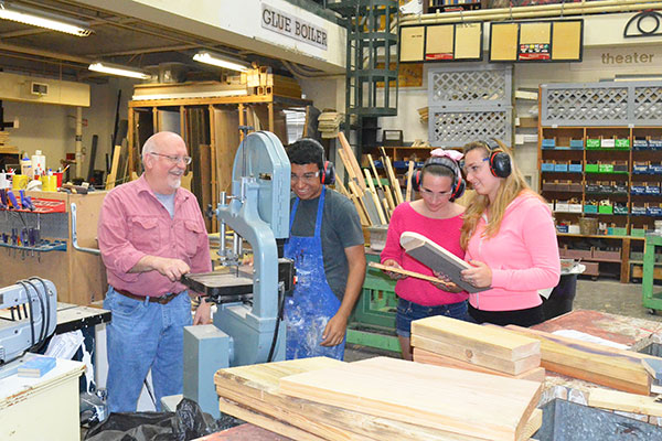 Three theatre students and professor Brian Reed in the workshop.
