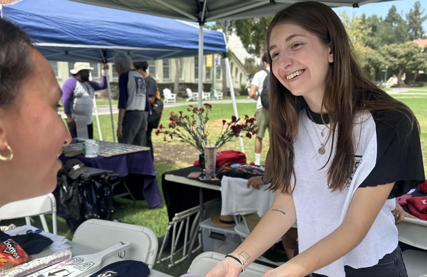 Female Whittier student handing promotional materials to fellow female student advertising their organization on campus