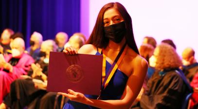 Whittier College student holding certificate on stage 