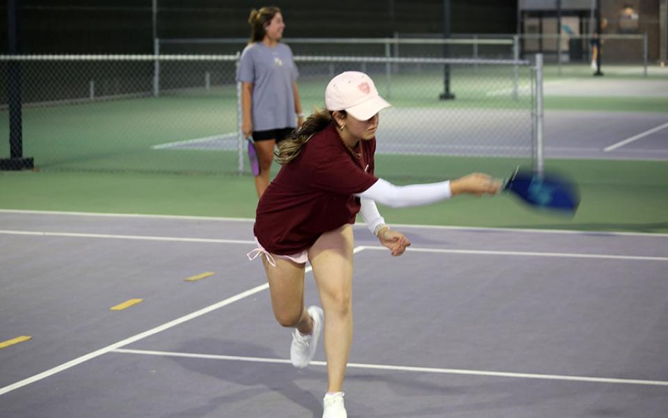 Staff member hitting a pickleball