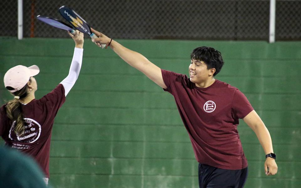 Staff member and student playing pickleball