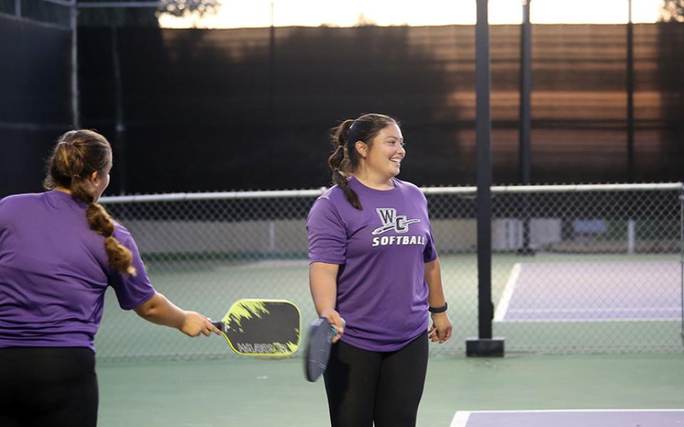 Two students playing pickleball