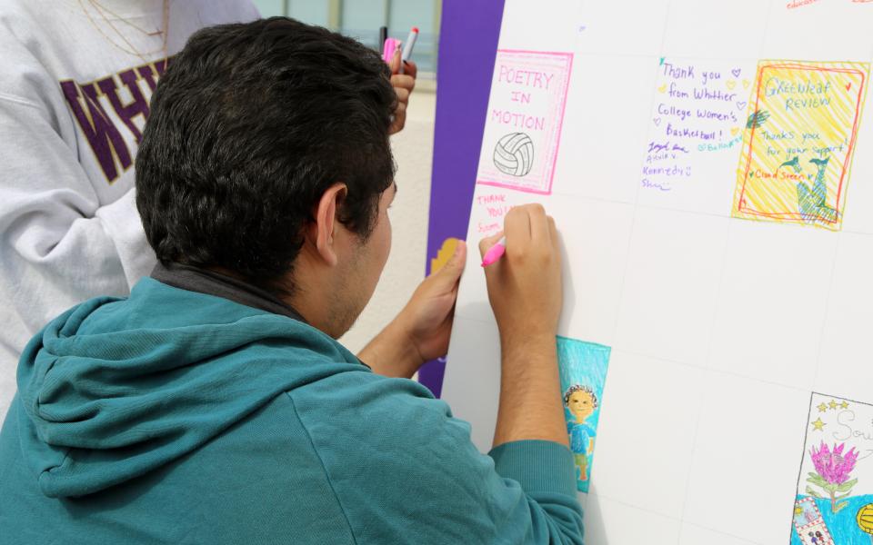 Student signing Big Poet Give wall